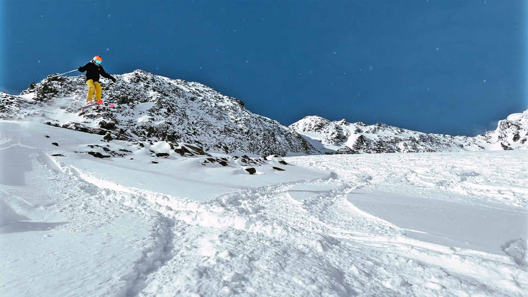 Stubai Glacier skier jumping off rock into snow