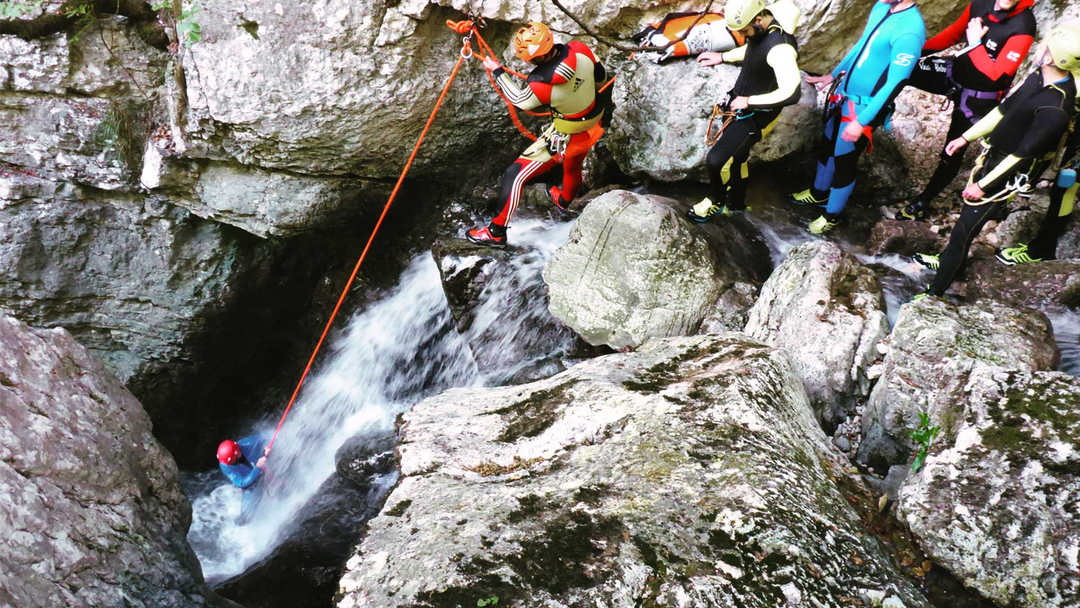 Person abseiling down a waterfall during a canyoning event.
