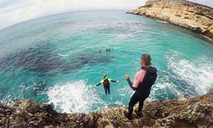 Woman leaping into the Mediterranean during coasteering in Mallorca, Spain.