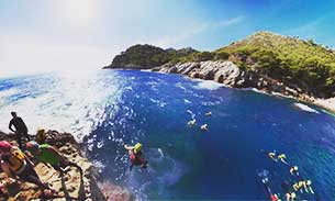 Person jumping off a cliff into the sea whilst coasteering in Mallorca, Spain.