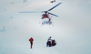 Helicopter above skiers on snowy mountain.