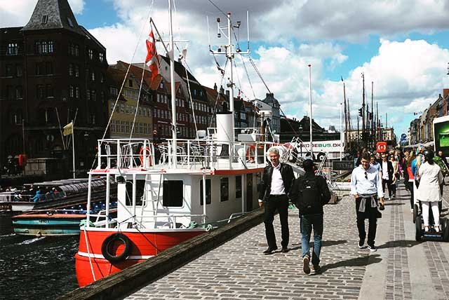 People walking past boats on a quayside