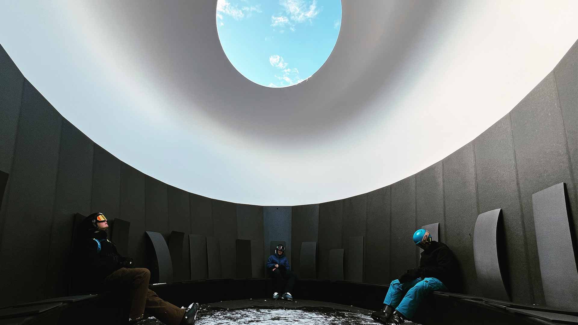 People sitting in a domed art installation, viewing the sky
