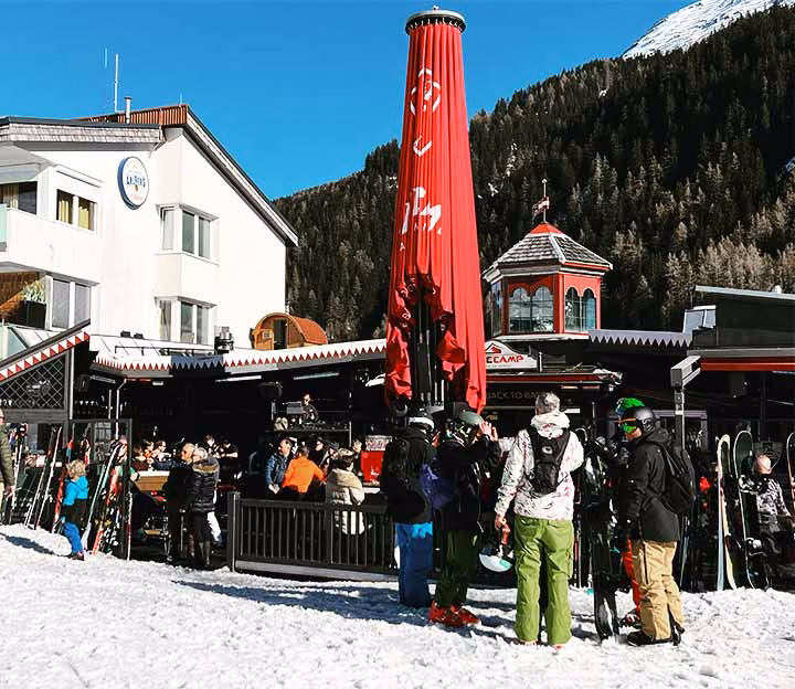 People standing in front of an apres ski bar on the snow