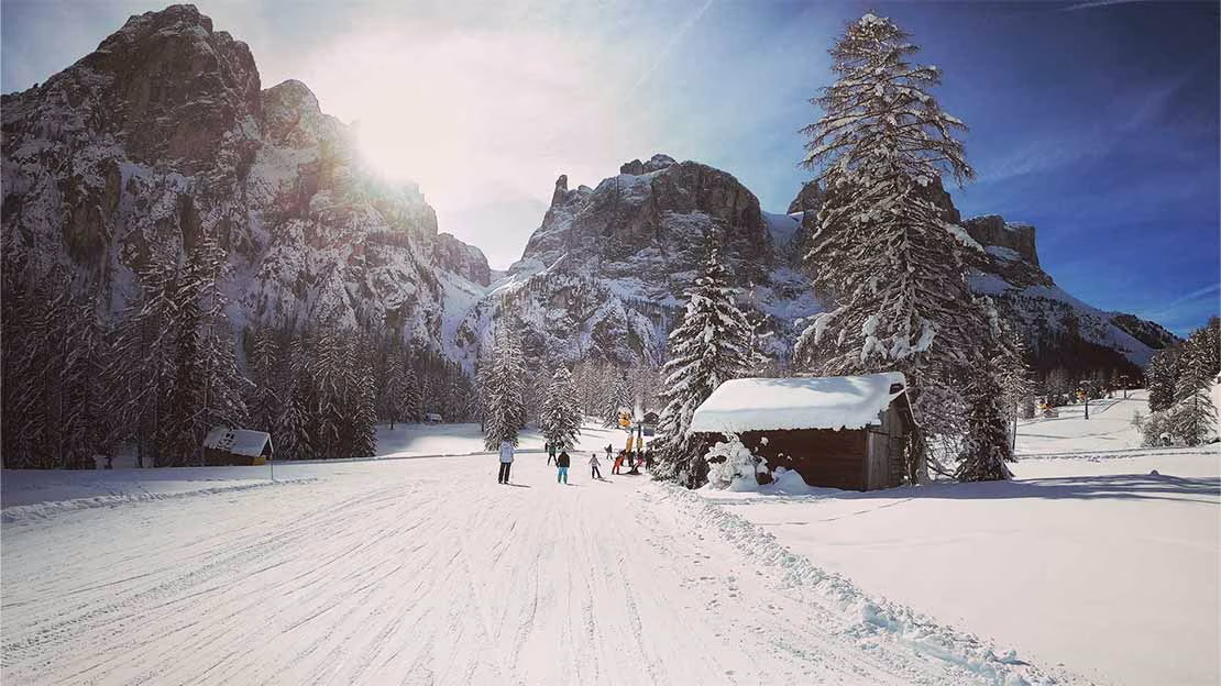 Skiers gliding along a ski piste in front of the Dolomite mountains