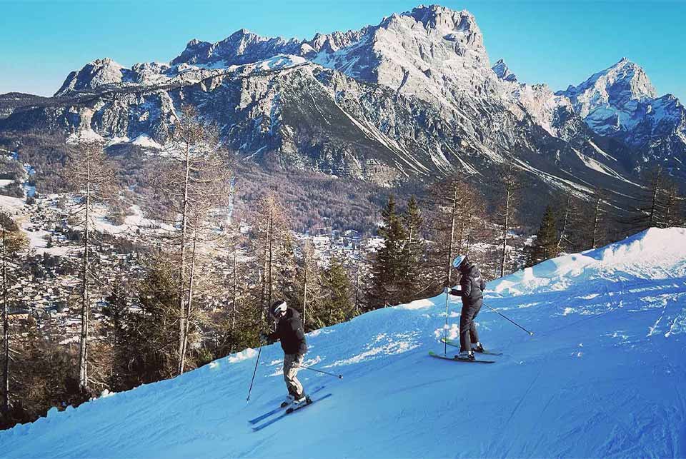 Two people skiing down a slope in Cortina