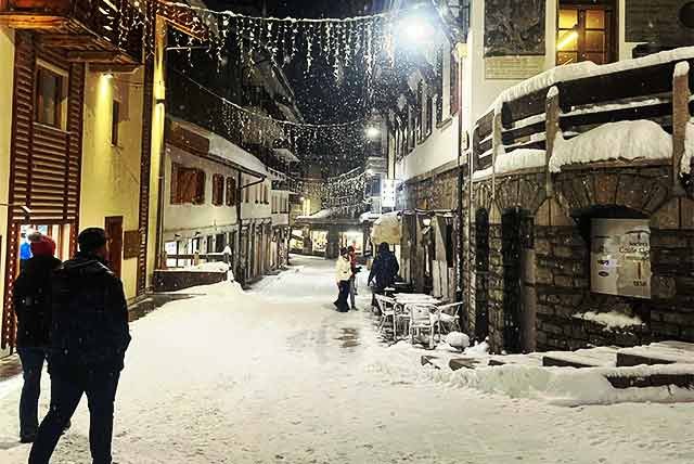 people walking at night on a snowy street