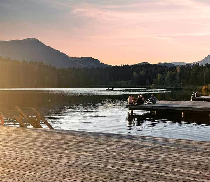 People lying on the deck of an alpine lake