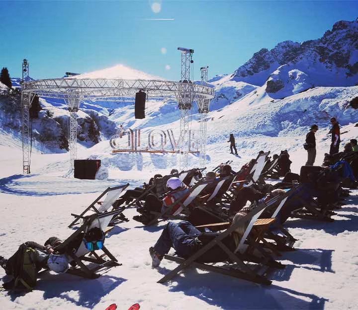 People on deck chairs at a mountain hut in the snow