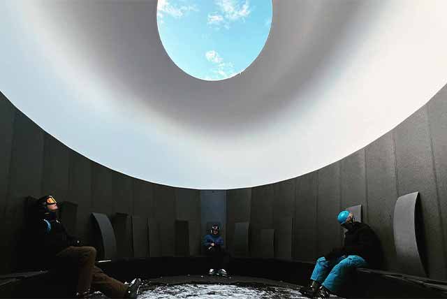 People sitting in a domed art installation, viewing the sky