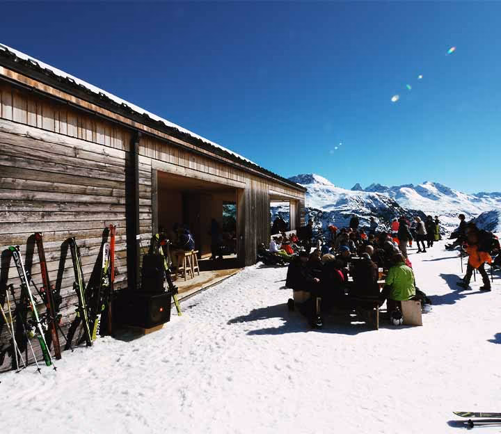 People sat outside a ski hut in the snow