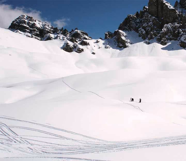 Distant skiers standing in front of mountains