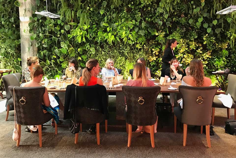 People dining in a restaurant featuring a grass interior wall