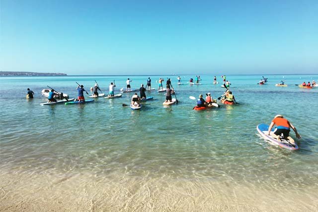 People entering the sea with paddle boards