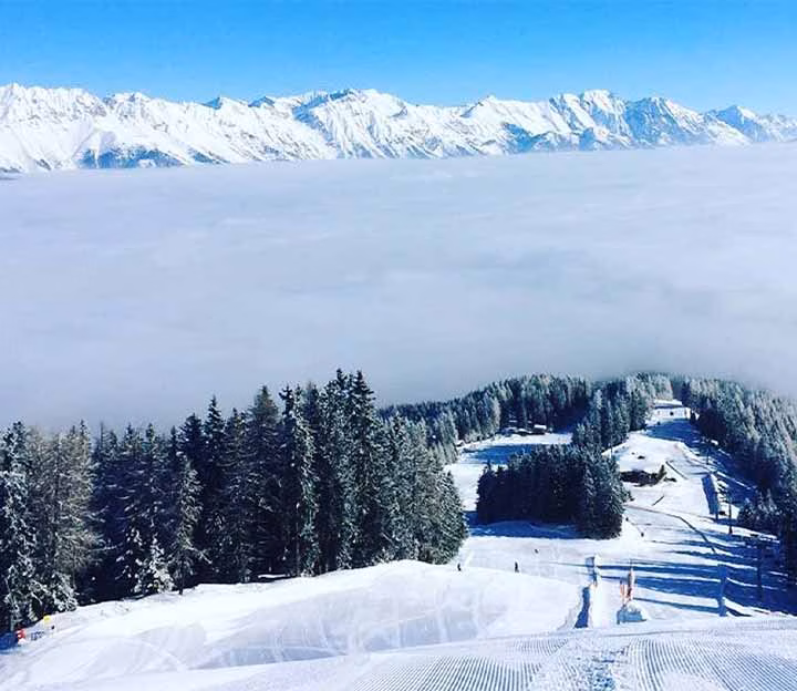 Snowy ski slope above a cloudy valley