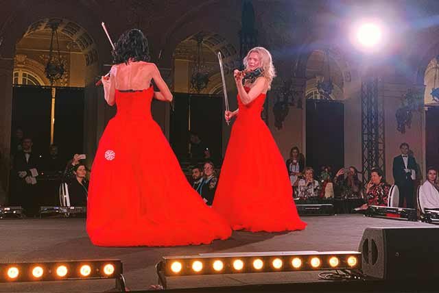 2 violinists performing on a stage