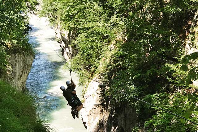 Two people on a zip line over a river