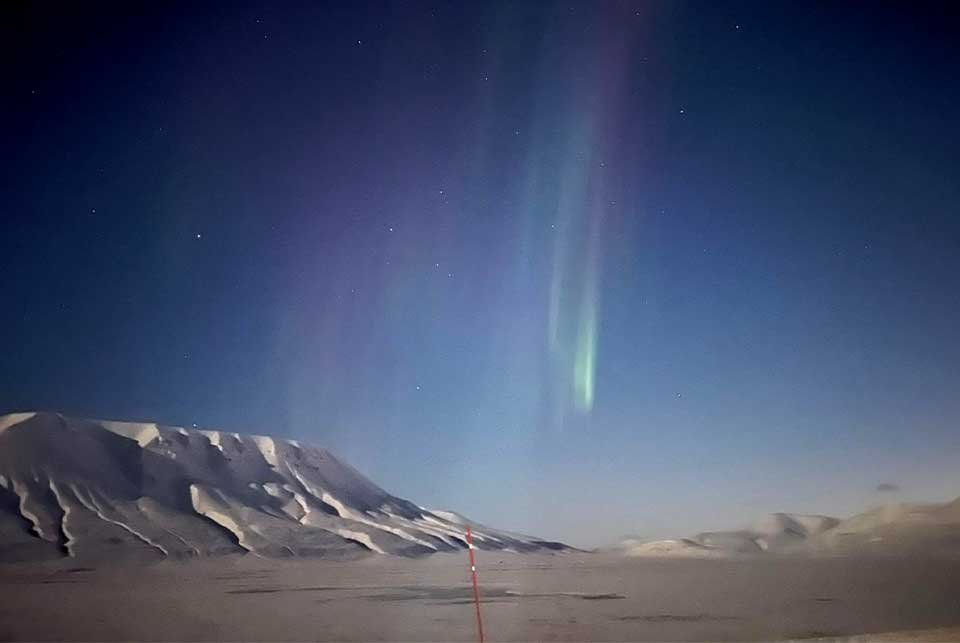 Nothern lights over a snowy valley in Svalbard