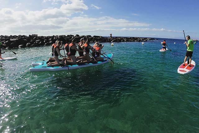 Group of people sharing a paddle board