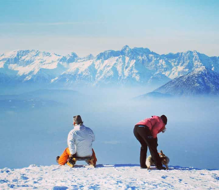 2 people tobogganing on a snowy mountain