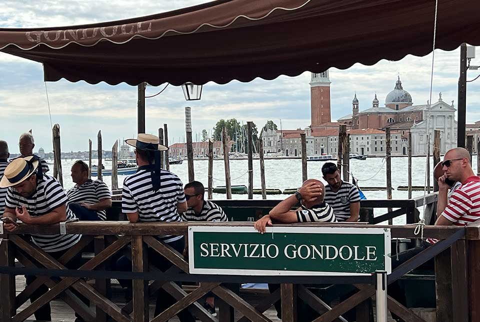 Gondoliers sat on a quayside in Venice