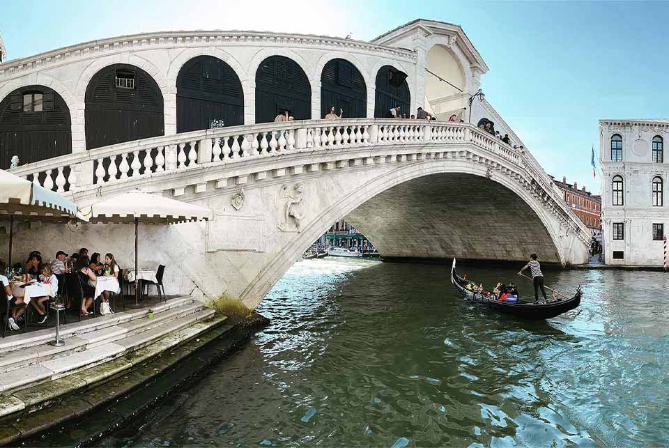 Gondola sailing under a bridge on a canal in Venice